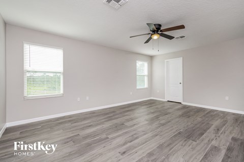the spacious living room with wood flooring and a ceiling fan