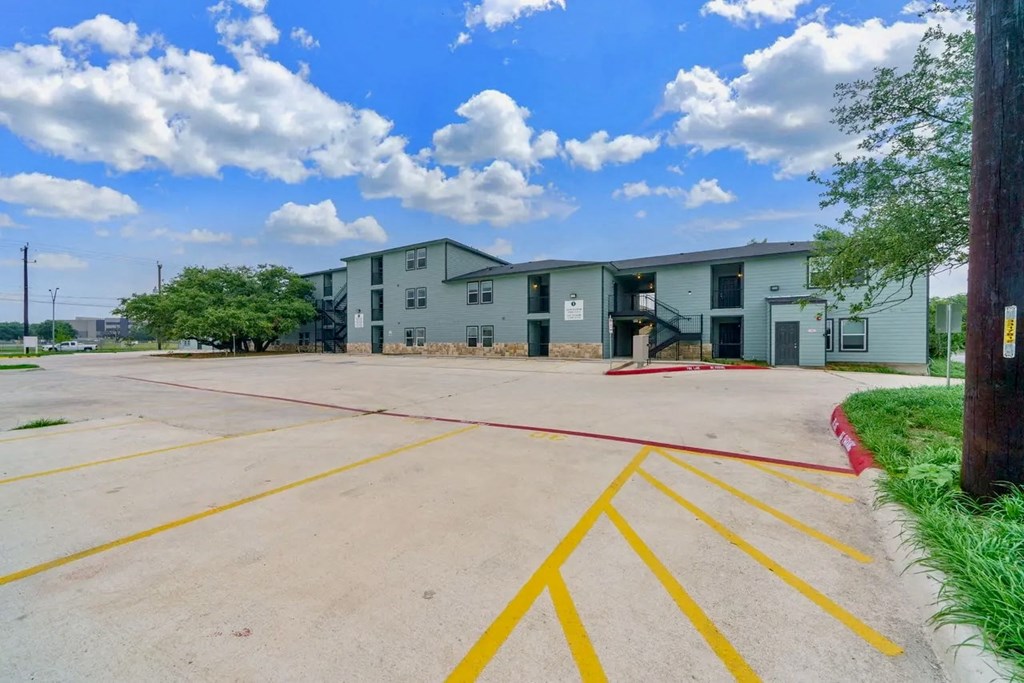 an empty parking lot with an apartment building in the background