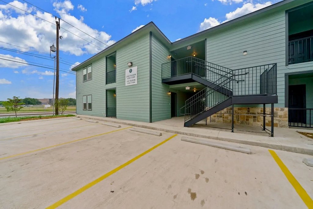 the front of a building with stairs and a parking lot