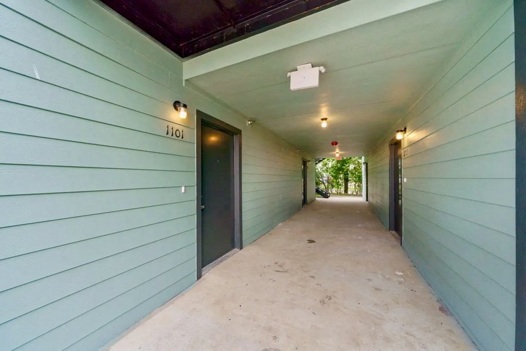 a long hallway with blue wood sided walls and doors