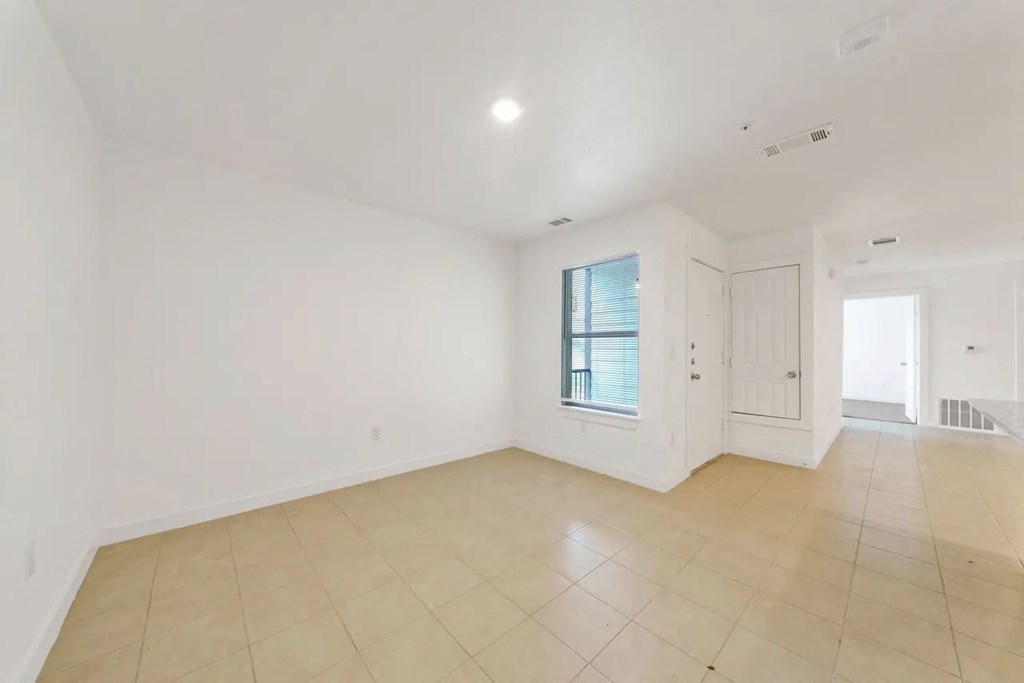 an empty living room with white walls and tiled floors
