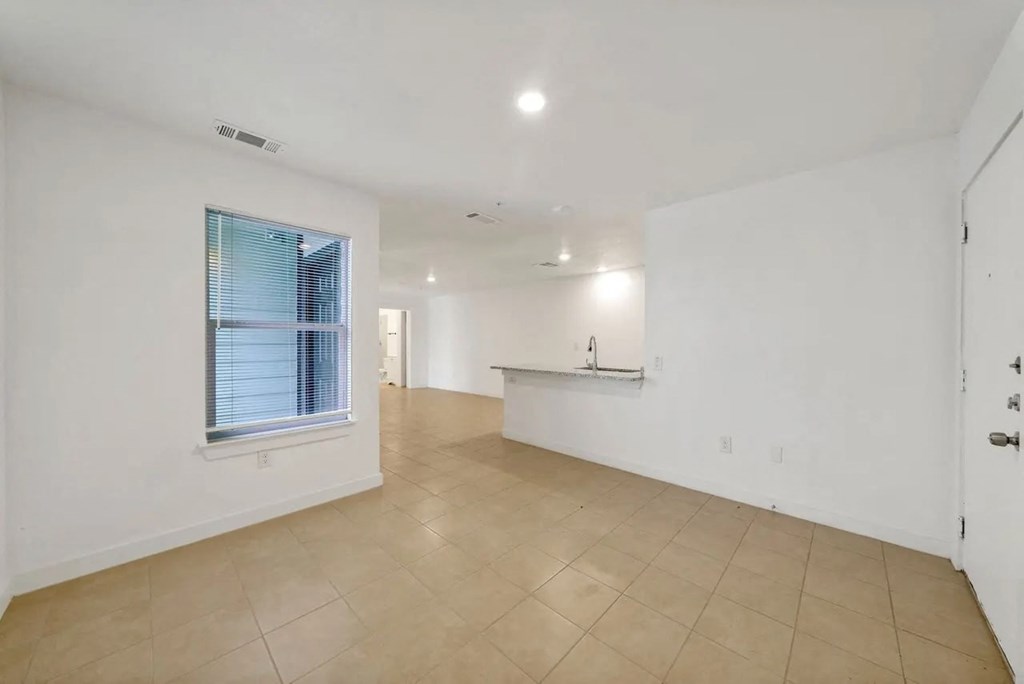 the living room and kitchen of a home with white walls and a window