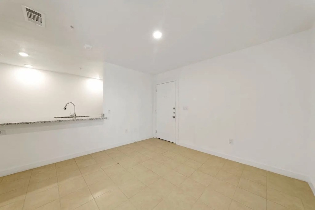 an empty living room with white walls and a sink