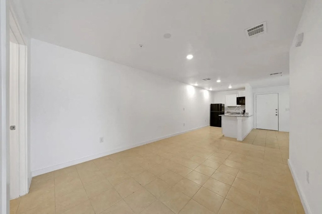 an empty living room and kitchen with white walls and tiled floors