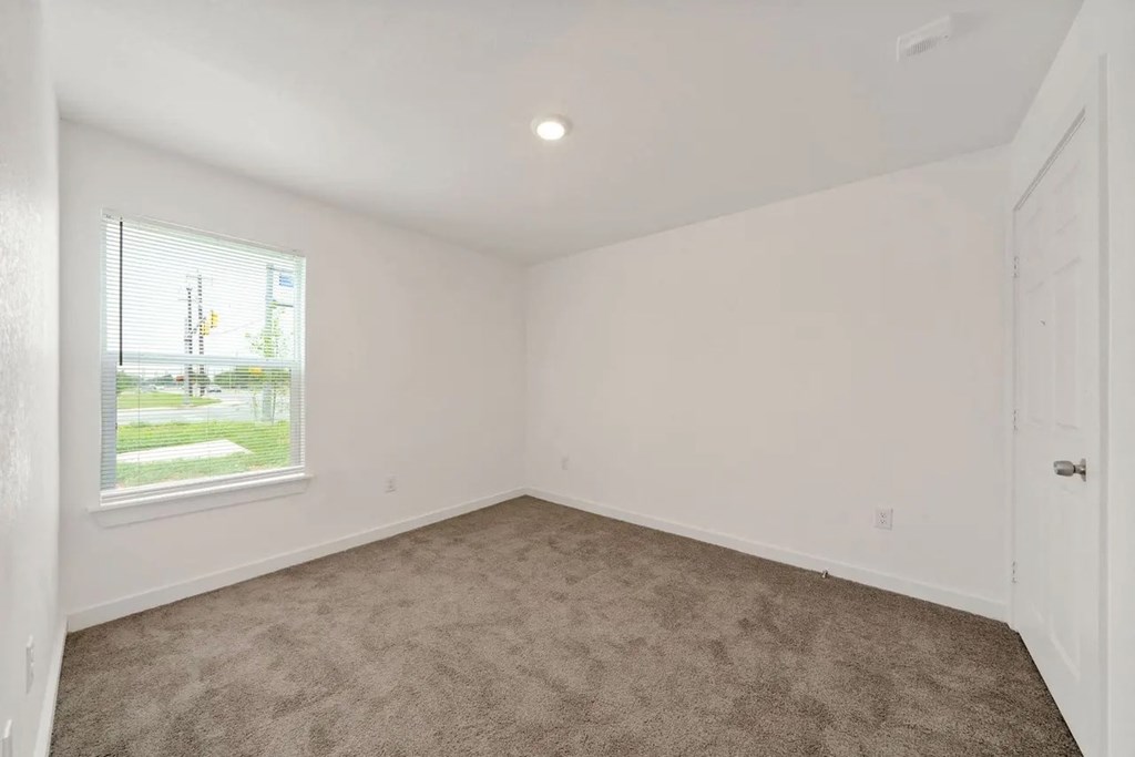 an empty living room with a window and carpet