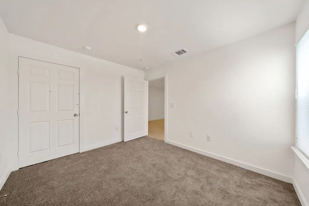 an empty living room with white walls and carpet