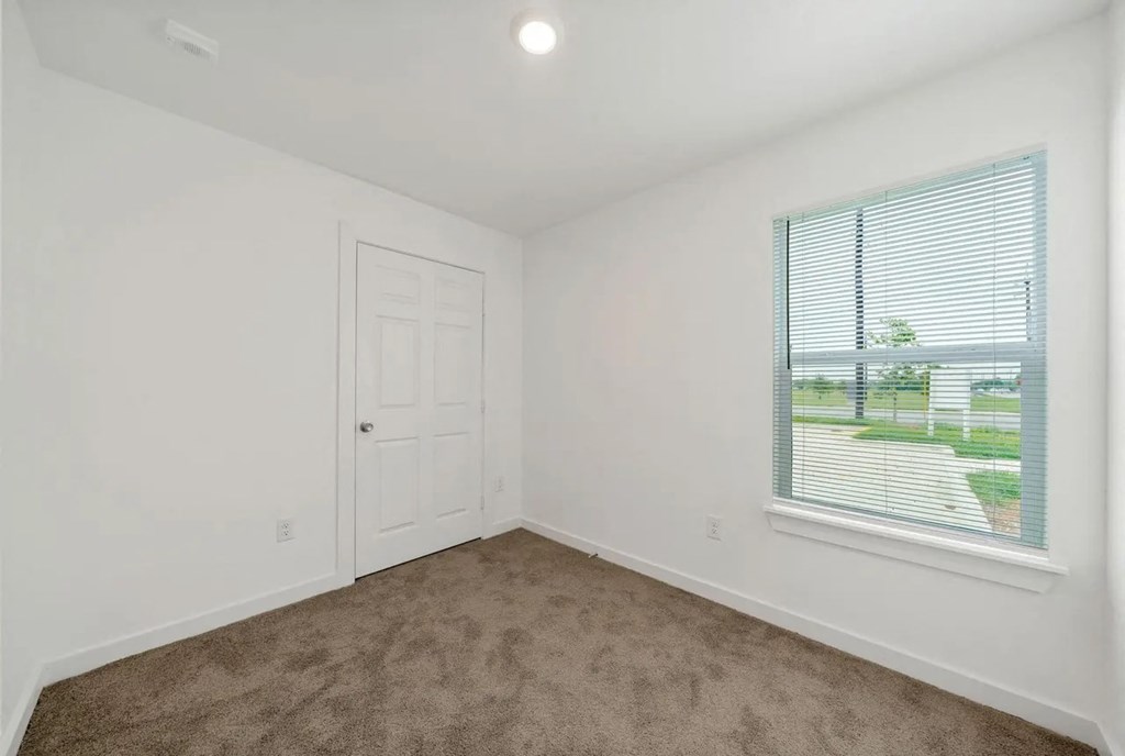 an empty bedroom with a window and a door