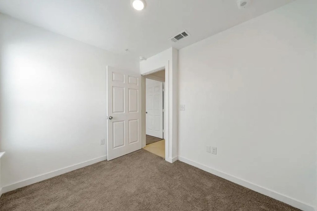 a bedroom with white walls and a door to a closet