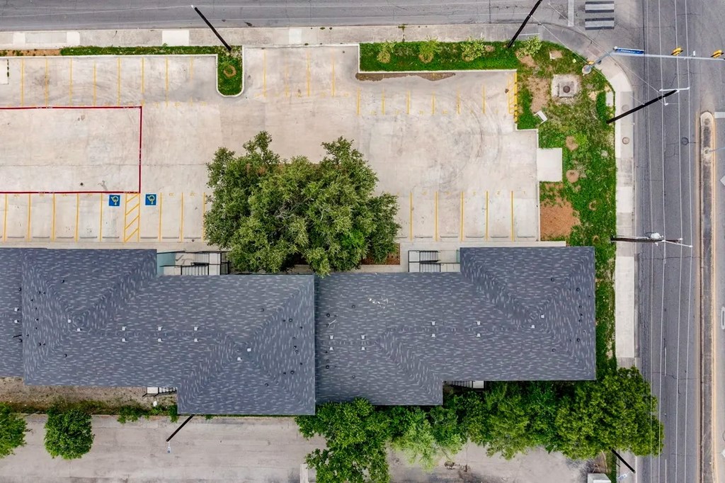 an aerial view of a parking lot and trees on the roof of a building