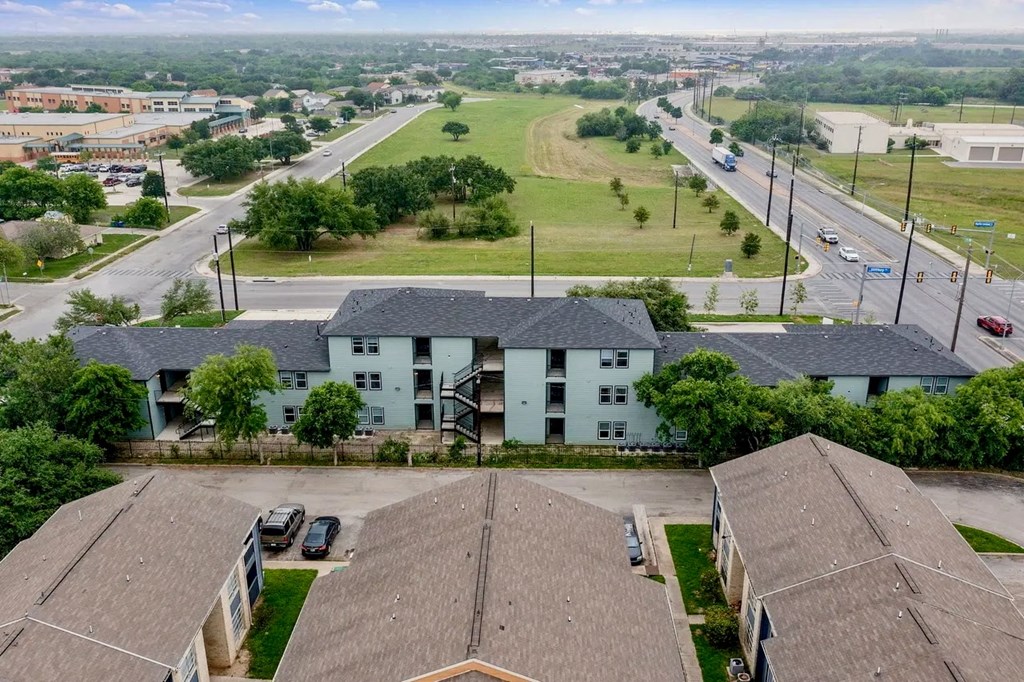 an aerial view of a white building with two roofs and a parking lot