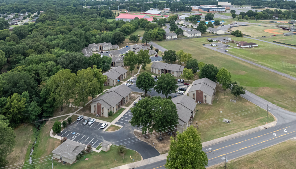 A large building surrounded by trees and a parking lot.