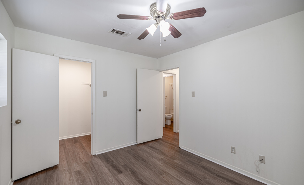 A room with a ceiling fan and wooden floors.