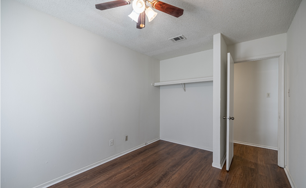 A room with a ceiling fan and wooden floors.