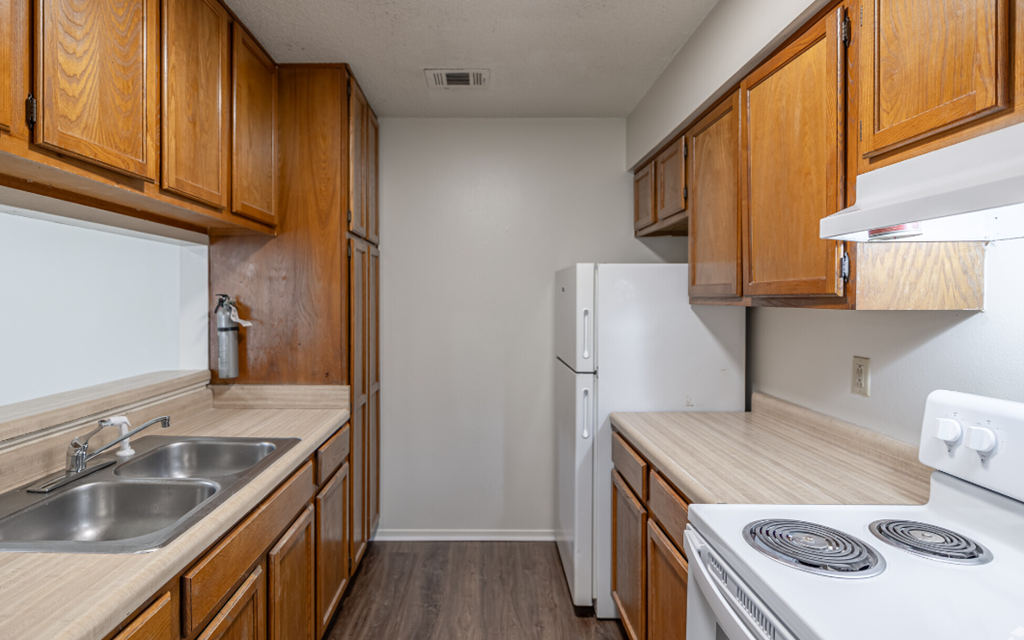 A kitchen with wooden cabinets and a white stove top oven.