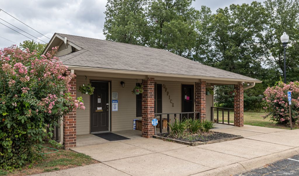 A small building with a brown roof and a brick pillar on the front.