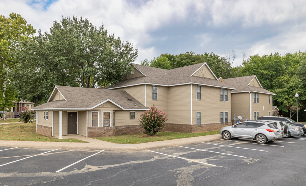 Apartment complex with a parking lot in front.