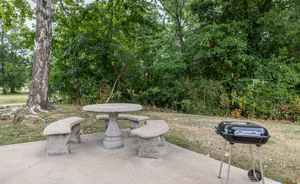 A grill is on a patio table with four chairs around it.