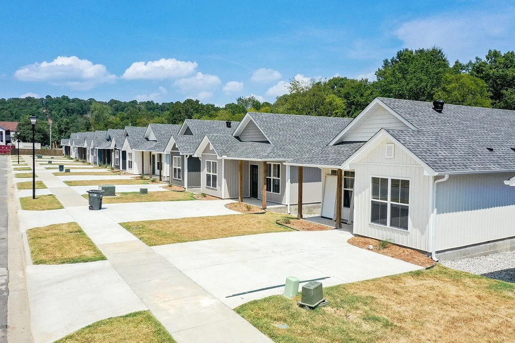 a row of white manufactured homes with grass and trees