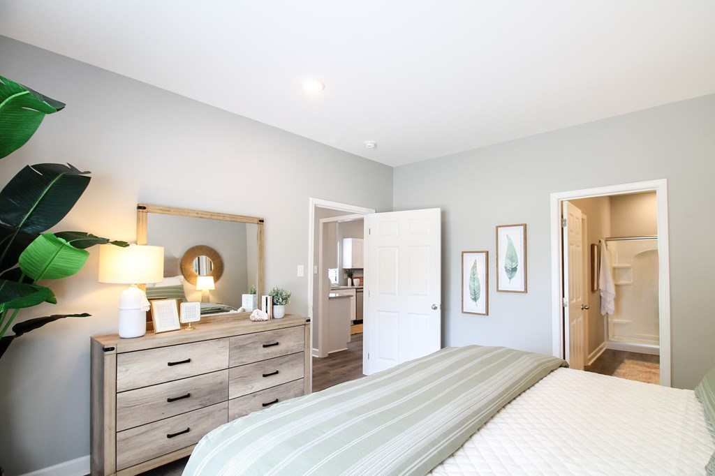 a bedroom with a bed and a dresser and a bathroom