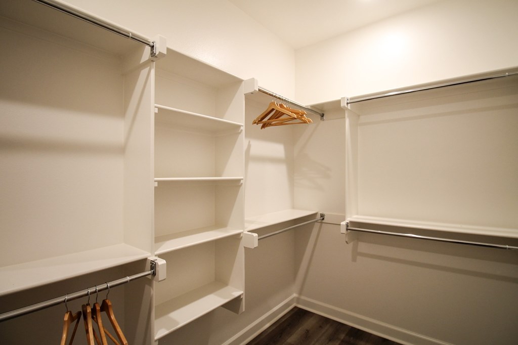 a walk in closet with white shelving and a hanger