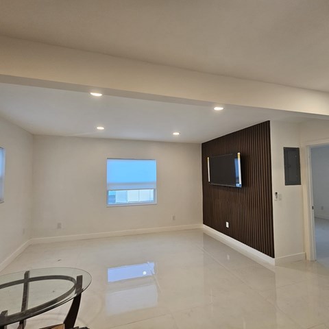 A modern living room with a glass table and a flat screen TV mounted on the wall.