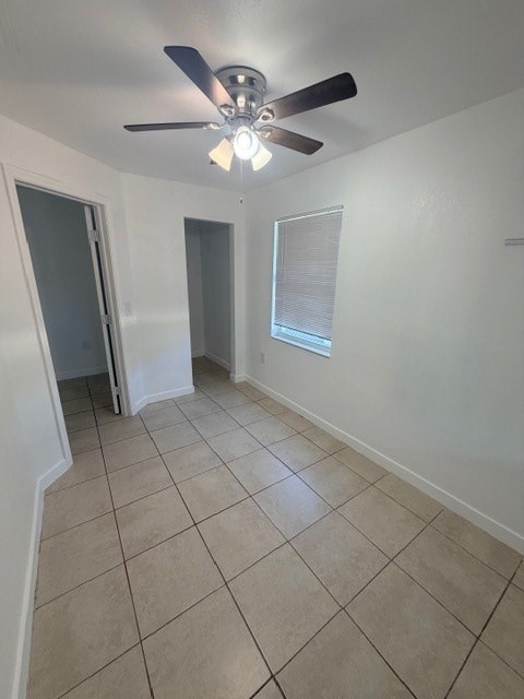 A room with a ceiling fan and tiled flooring.