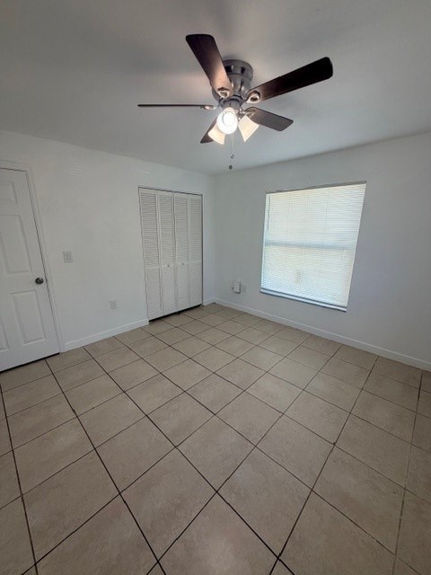 A room with a ceiling fan and tile flooring.