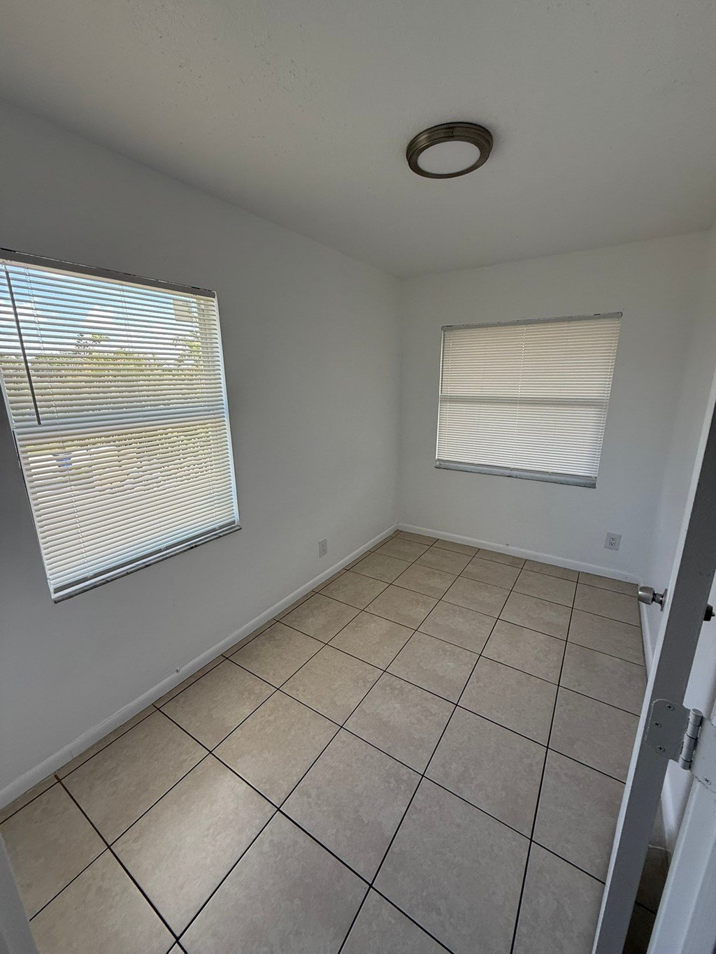 A room with a tiled floor and a window with blinds.