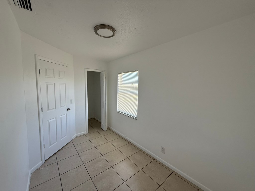 A room with a white door and a window with blinds.