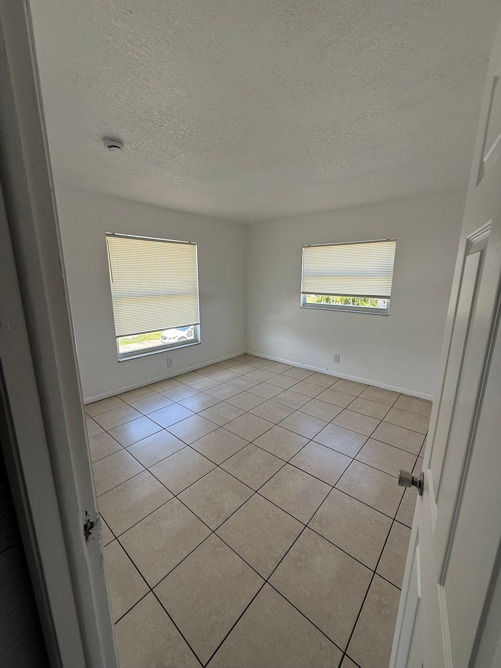 A room with white walls and tile flooring with a window.