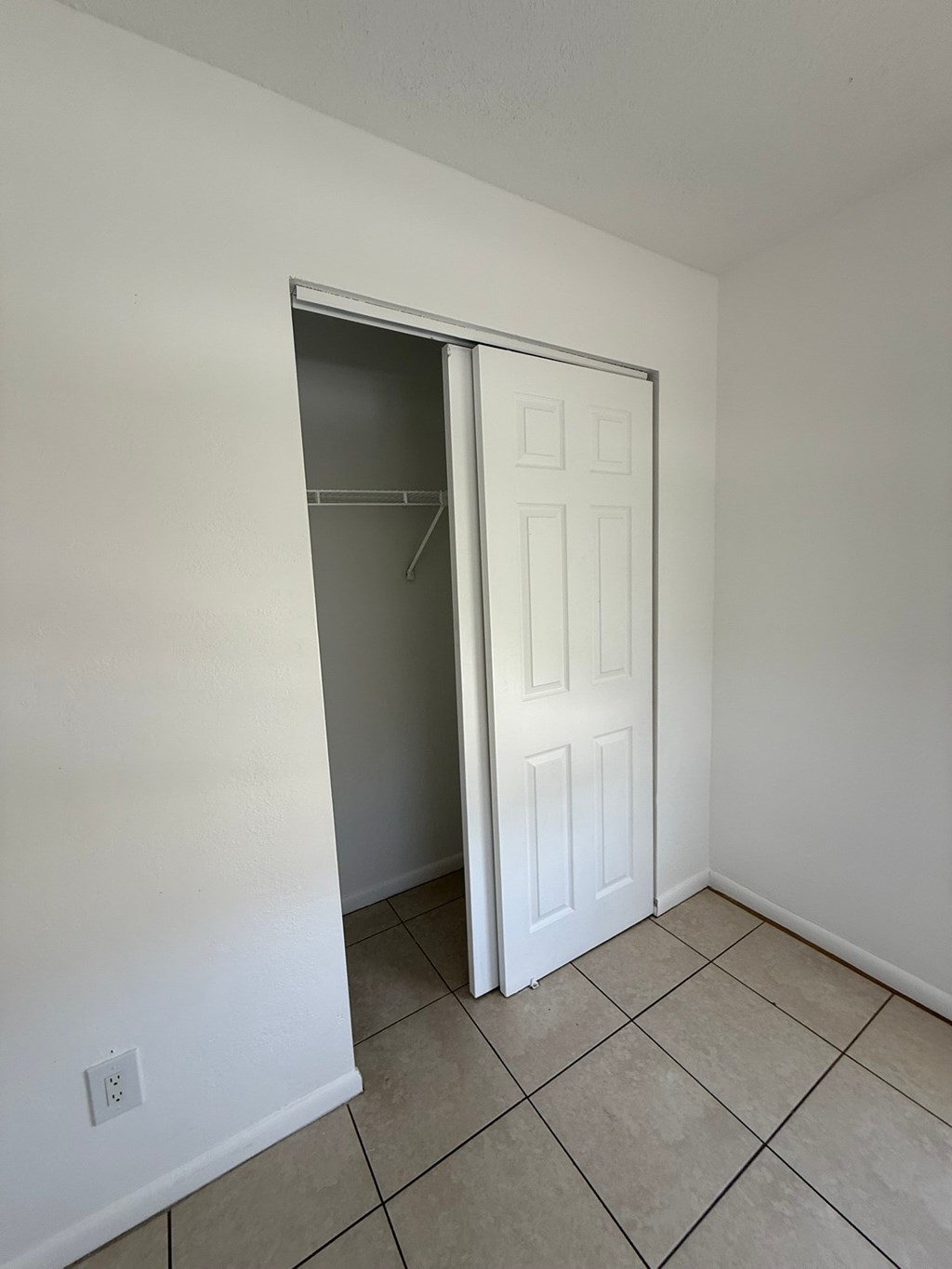 A white door is open in a room with tiled flooring.