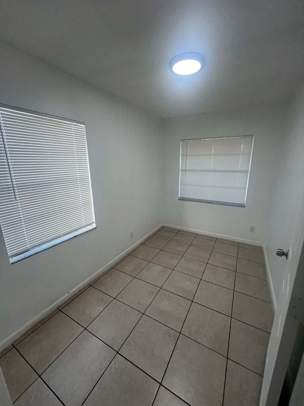 A room with tiled flooring and a window with blinds.