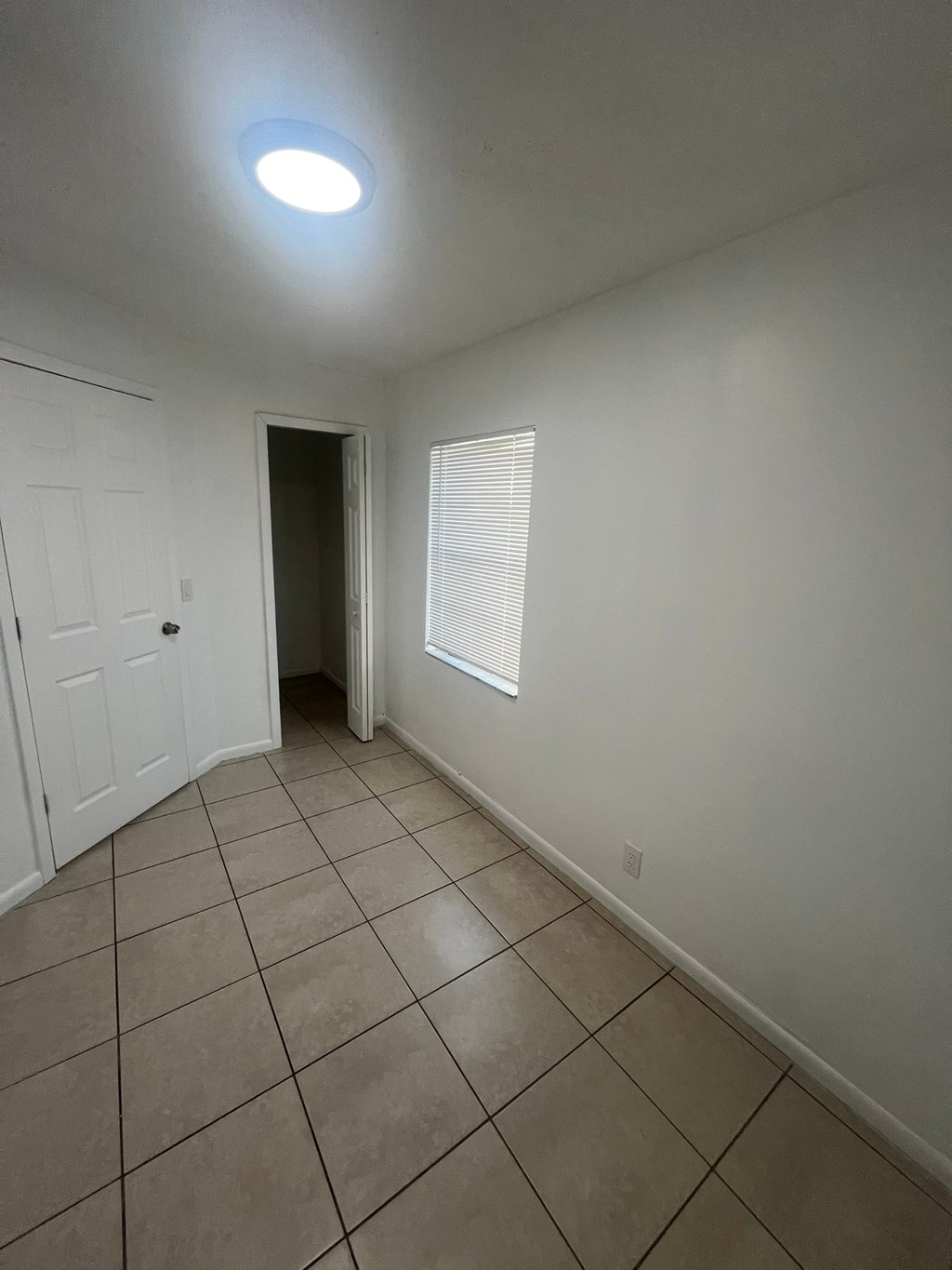 A room with a white door and a window with blinds.