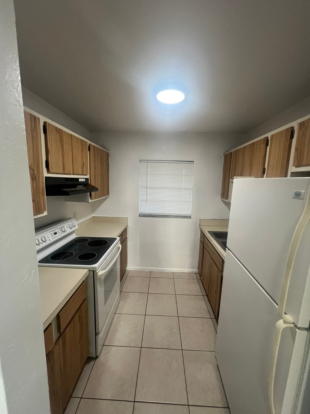 A kitchen with a white refrigerator, white stove, and white oven.