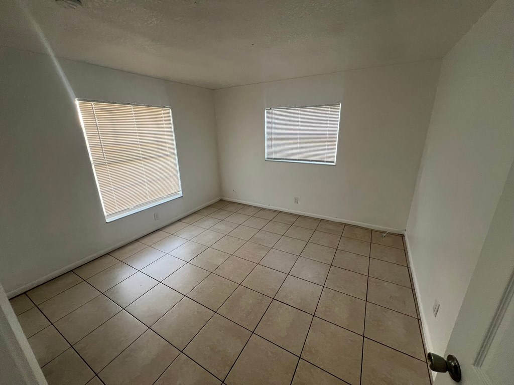 A room with tiled flooring and a window with blinds.