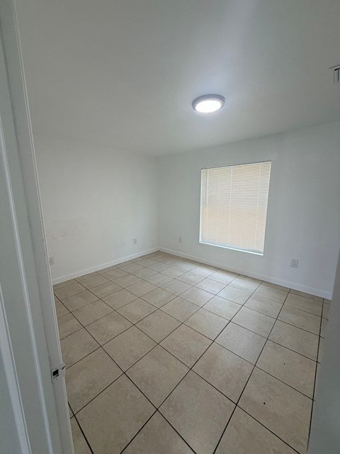 A room with a tiled floor and a window with blinds.