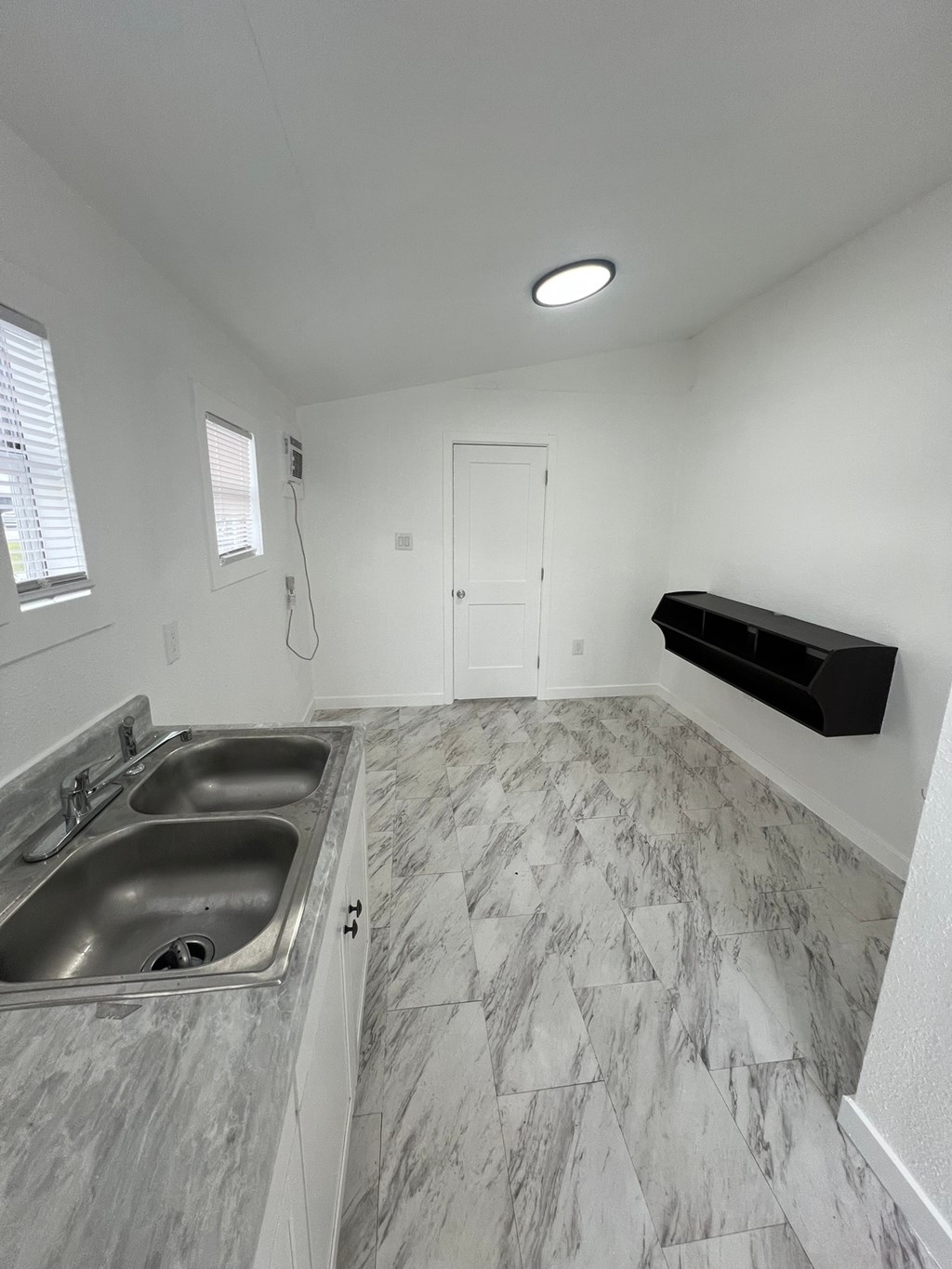 A bathroom with a marble floor and a white wall.
