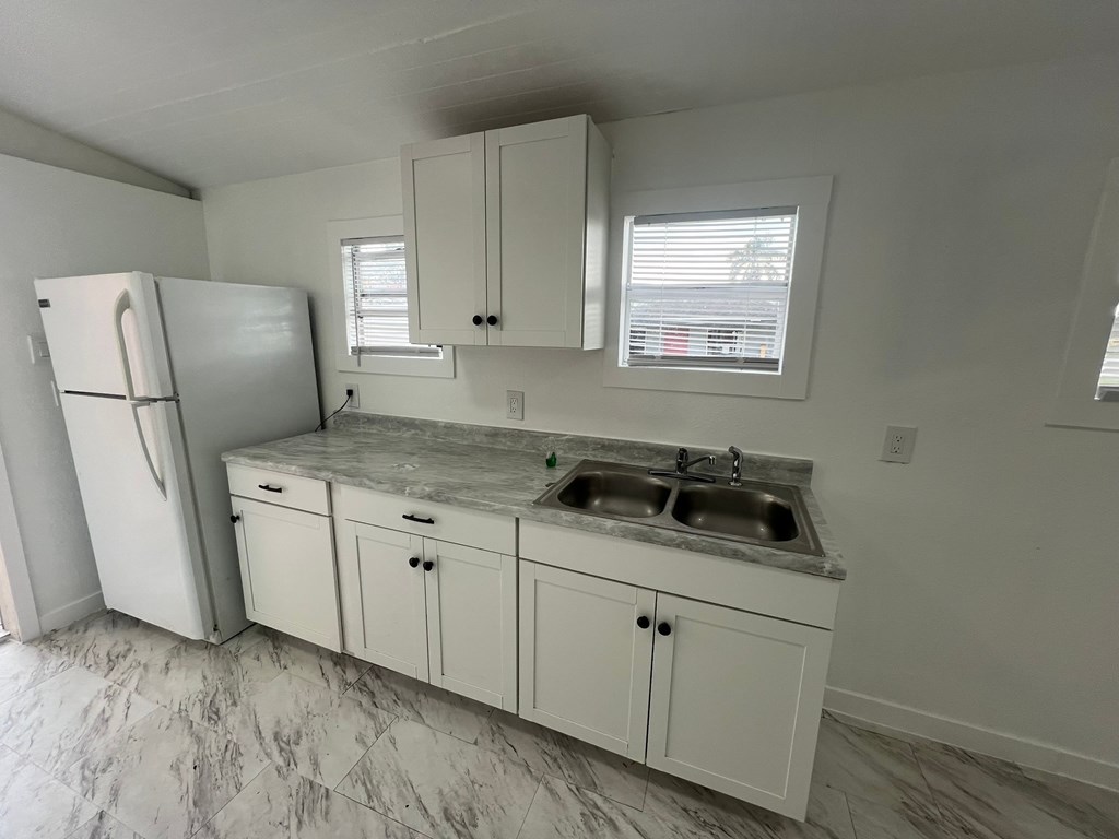A kitchen with a marble countertop and white cabinets.