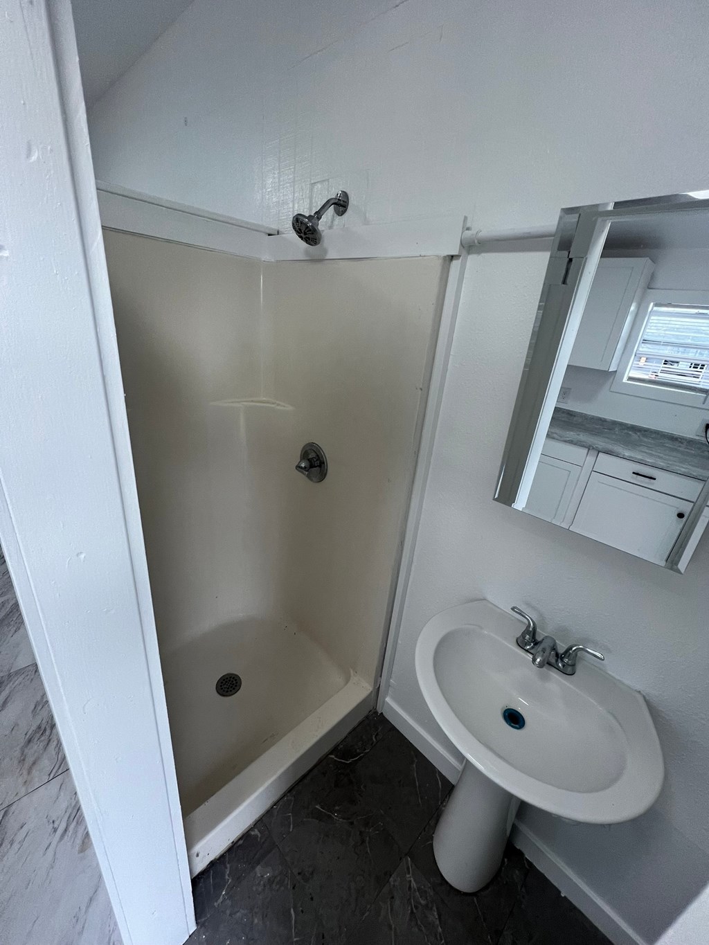 A white sink is in a small bathroom with a white tub.