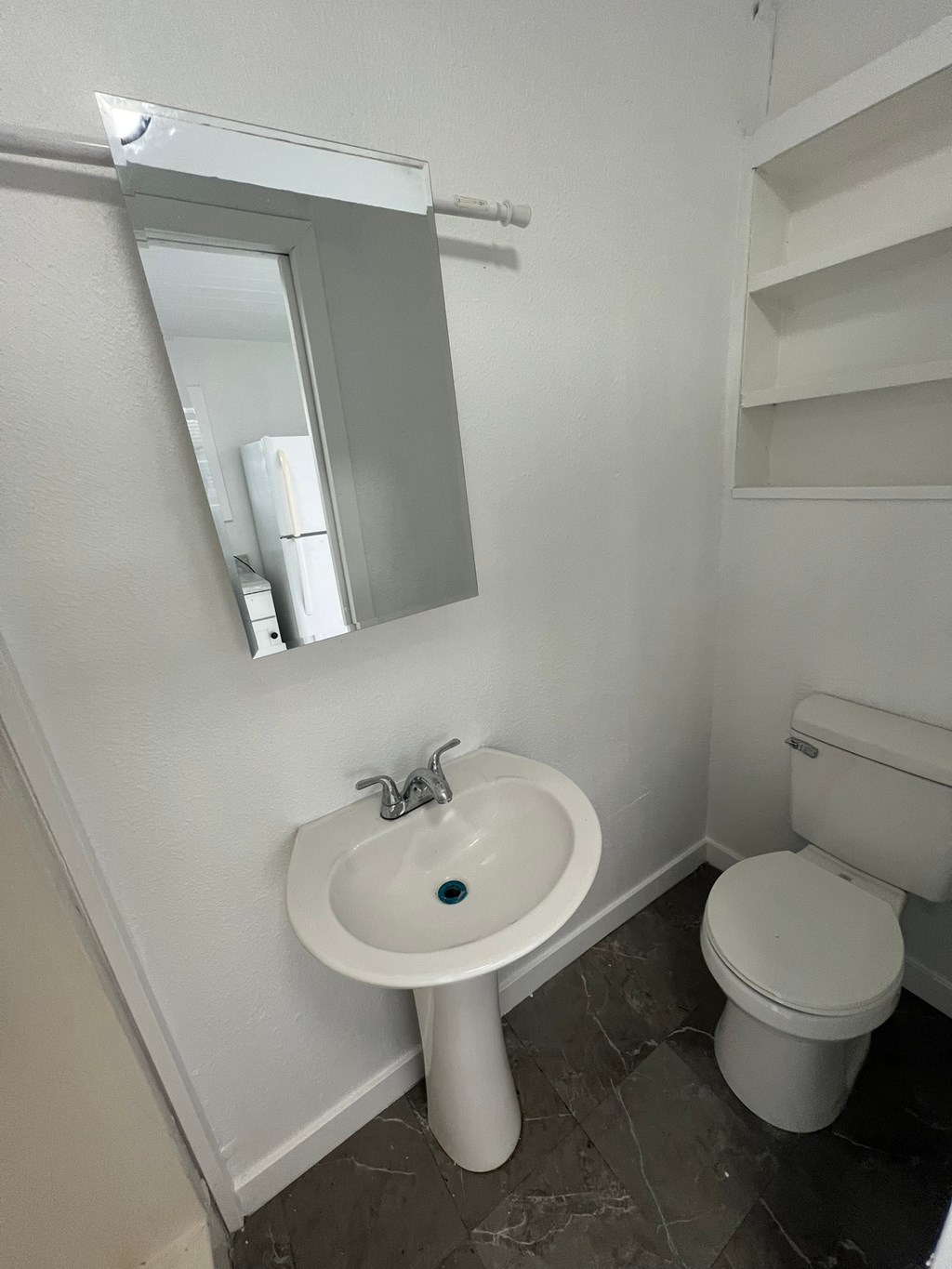 A white sink with a blue dot in the middle is under a mirror in a bathroom.