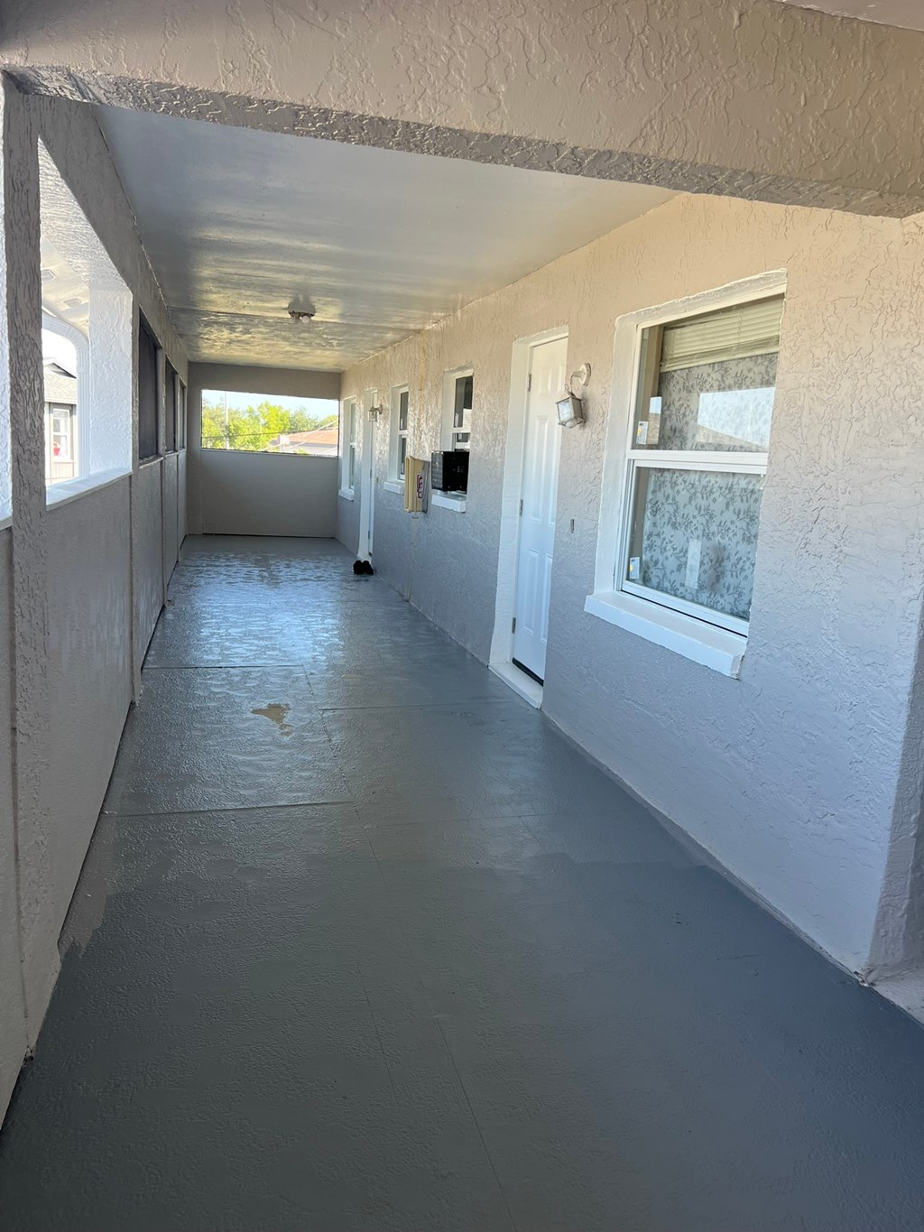 A long hallway with a white door and windows on the side.