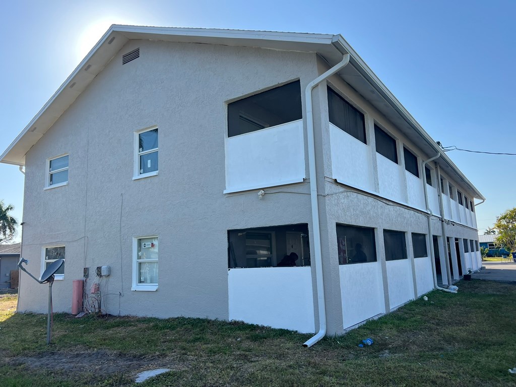 A two-story building with a white exterior and a balcony on the second floor.
