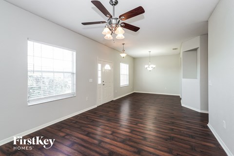 an empty living room with wood floors and a ceiling fan