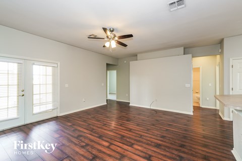 an empty living room with wood flooring and a ceiling fan