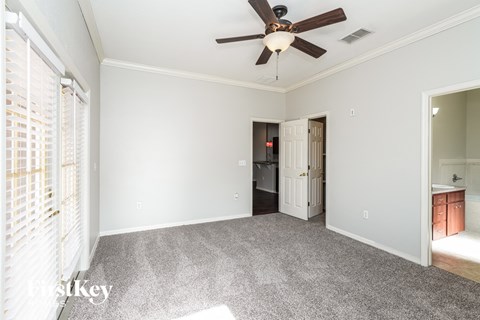 a living room with a ceiling fan and a door to a bathroom