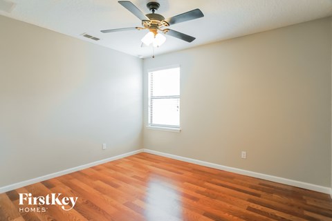 a bedroom with wood floors and a ceiling fan