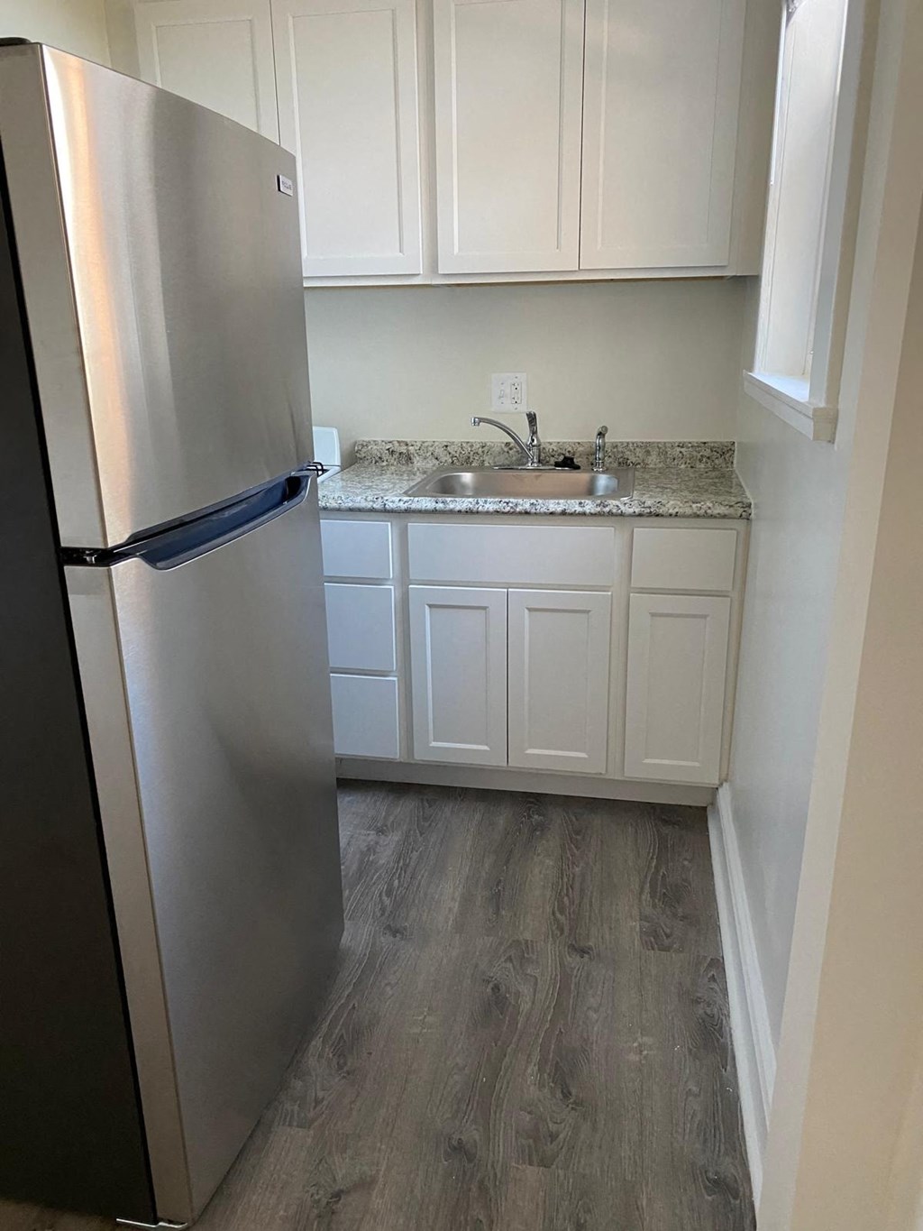 a kitchen with white cabinets and a stainless steel refrigerator
