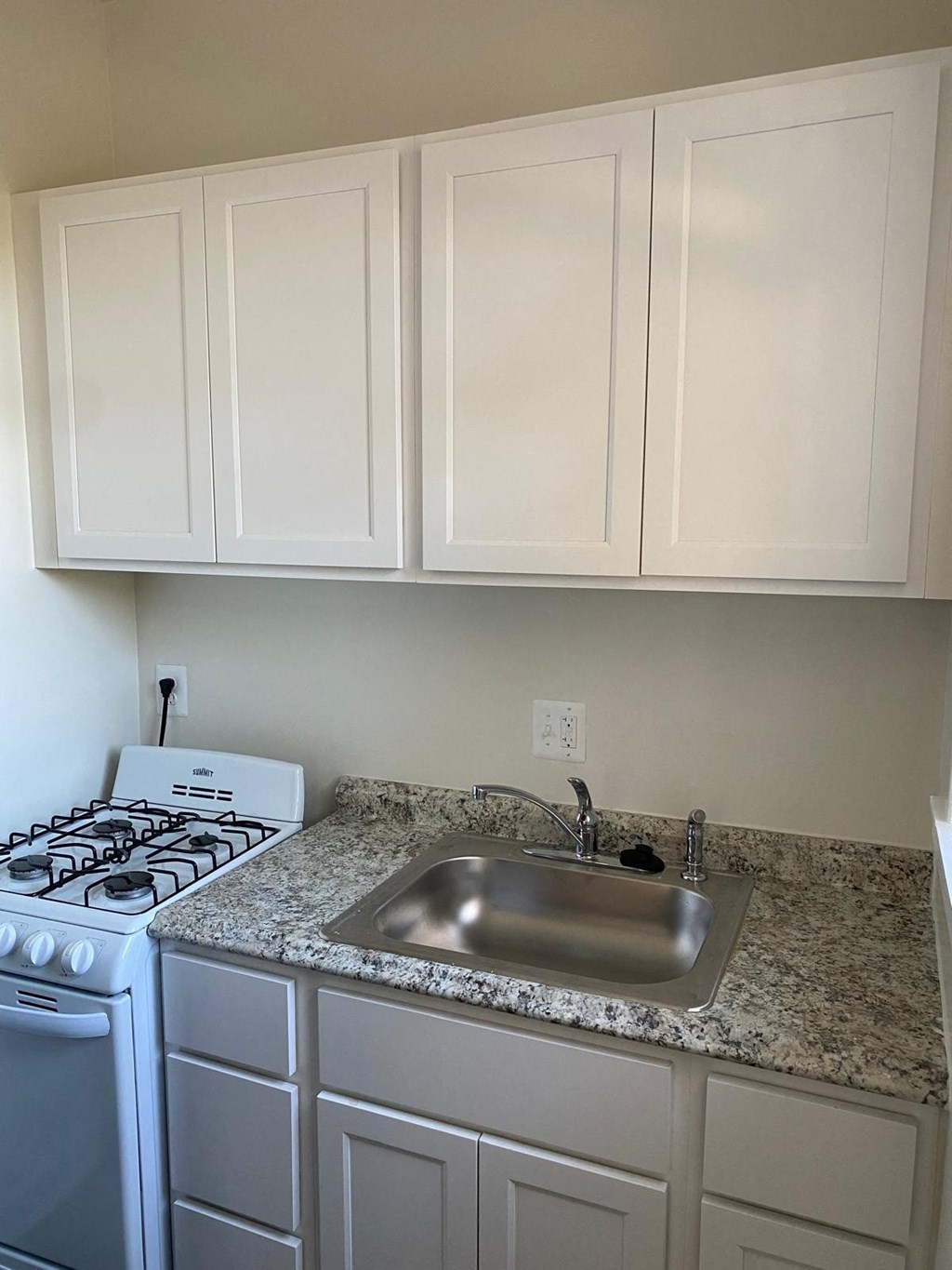 a kitchen with white cabinets and granite counter tops and a sink