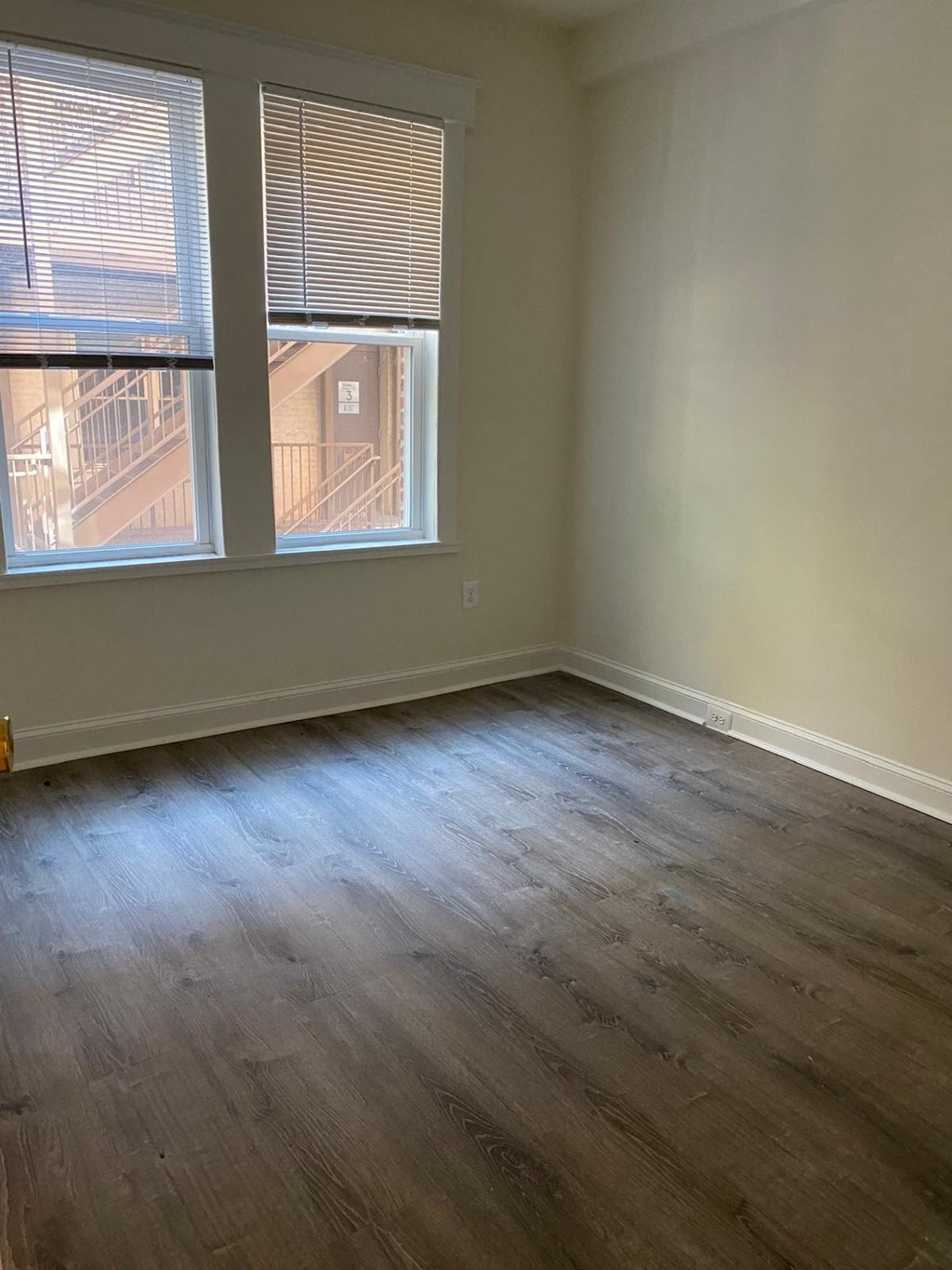 an empty living room with wood floors and two windows