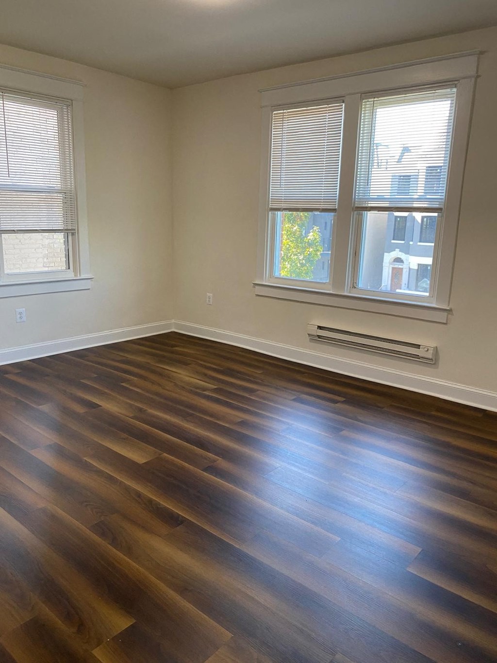 a room with a hard wood floor and three windows